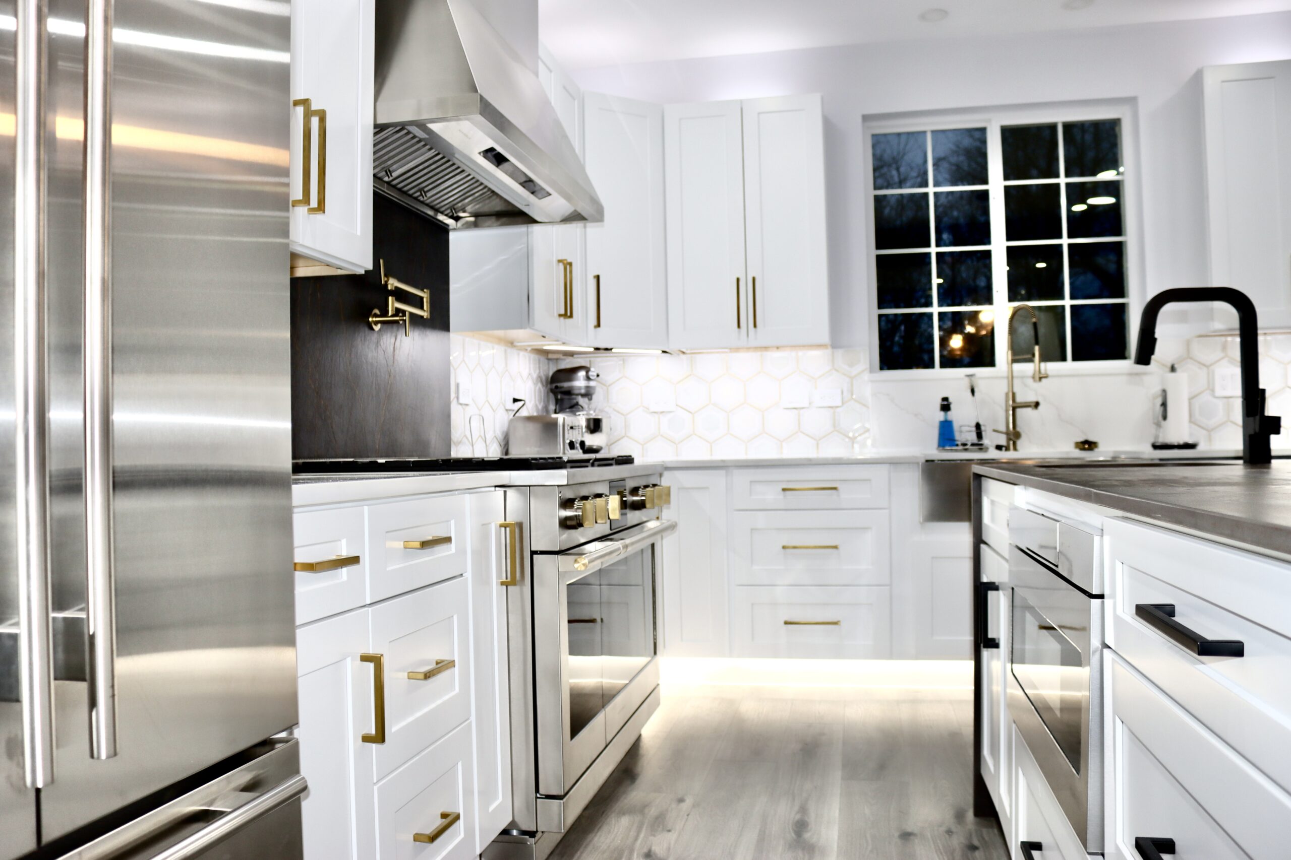 Modern kitchen renovation with white cabinetry and brass hardware