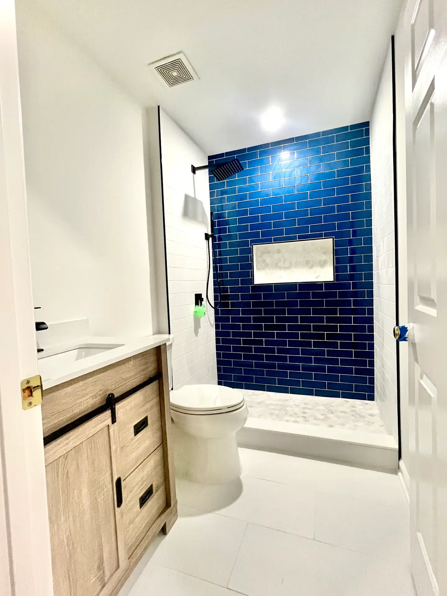 Guest bathroom remodel in Haymarket VA with blue subway tile shower, wood vanity, kid safety shower